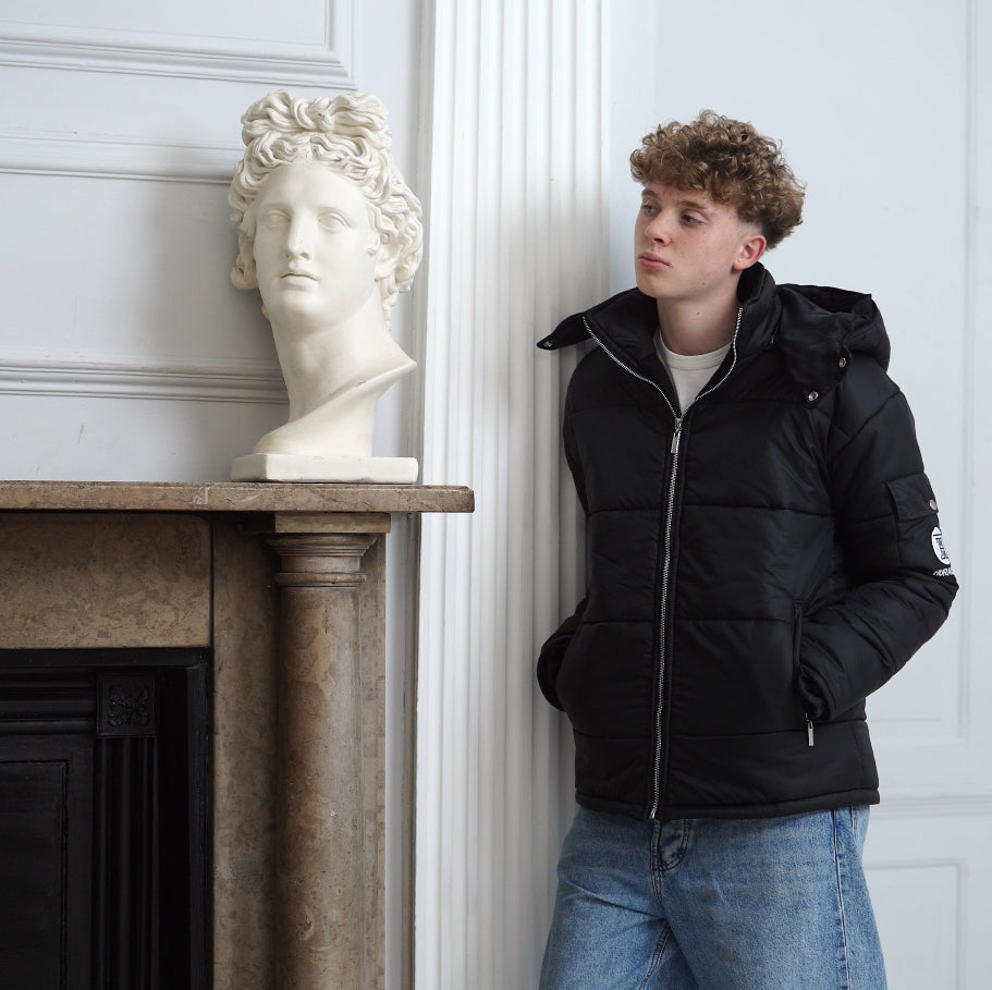 The Signature Huracan Men &amp; Women's Black Puffer Jacket hooded standing front side angled mantle piece 