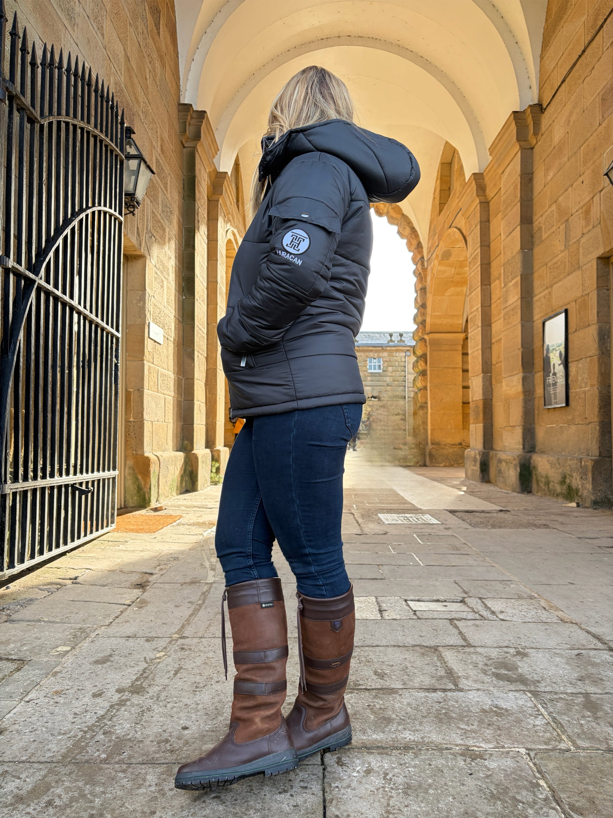 The Signature Huracan Men &amp; Women's Black Puffer Jacket hooded standing side back country girl